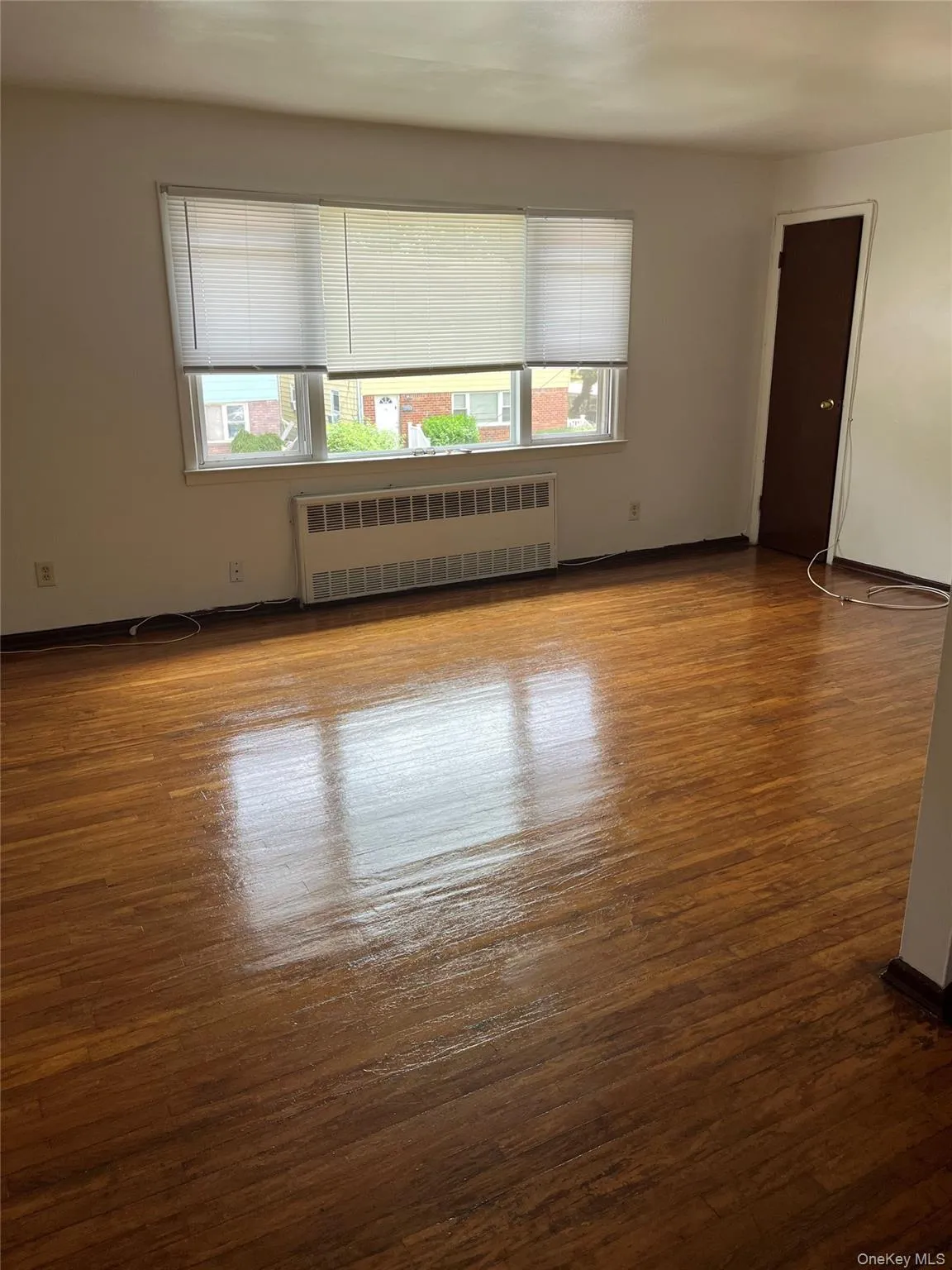 Empty room featuring plenty of natural light, radiator, and dark wood finished floors Empty room featuring plenty of natural light, radiator, and dark wood finished floors
