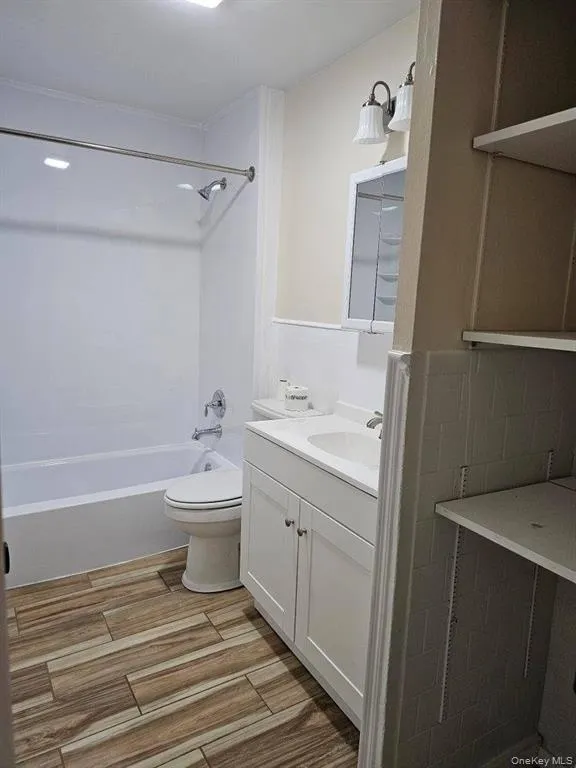 Bathroom featuring vanity, shower / bathtub combination, and wood tiled floors Bathroom featuring vanity, shower / bathtub combination, and wood tiled floors