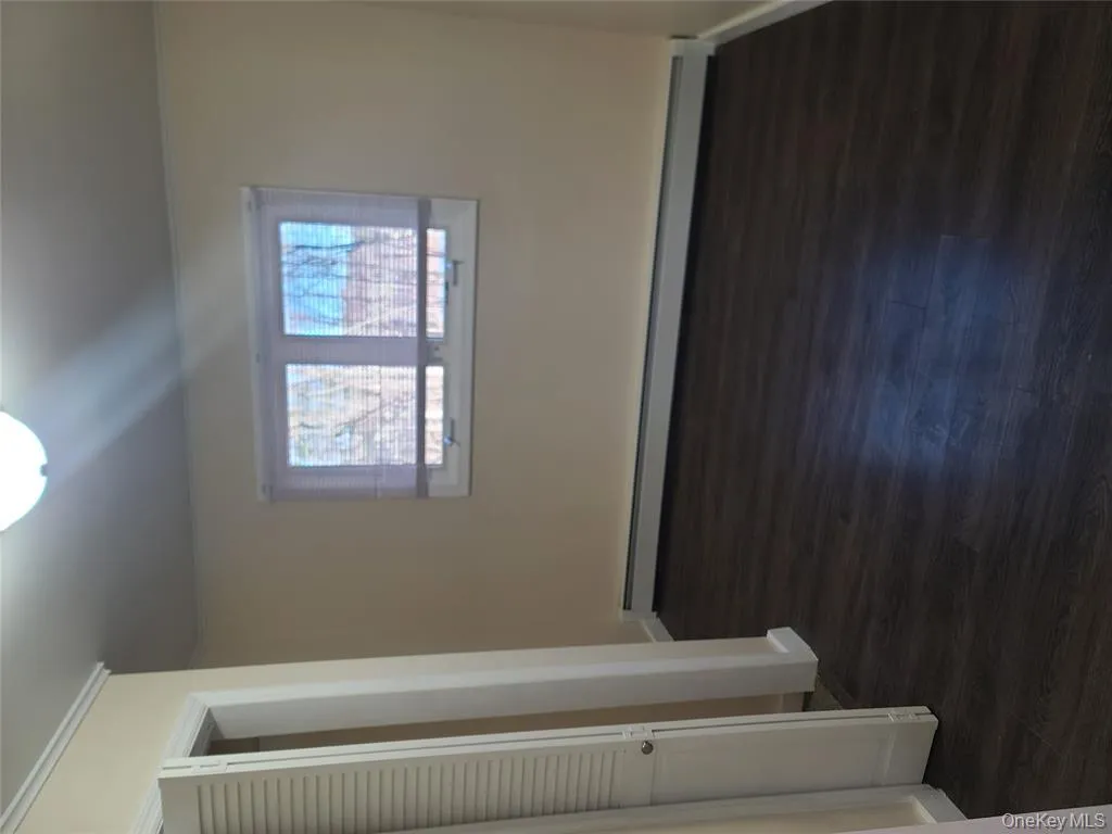 Unfurnished bedroom with dark wood-style floors, baseboard heating, and ornamental molding Unfurnished bedroom with dark wood-style floors, baseboard heating, and ornamental molding