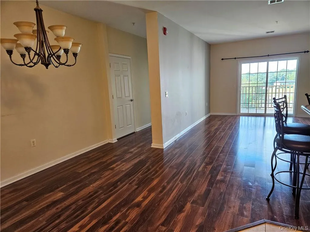 Open floor plan. Kitchen is on the near right and hallway to second bedroom and bath is on the left. Private balcony is just beyond the sliding glass doors. Open floor plan. Kitchen is on the near right and hallway to second bedroom and bath is on the left. Private balcony is just beyond the sliding glass doors.