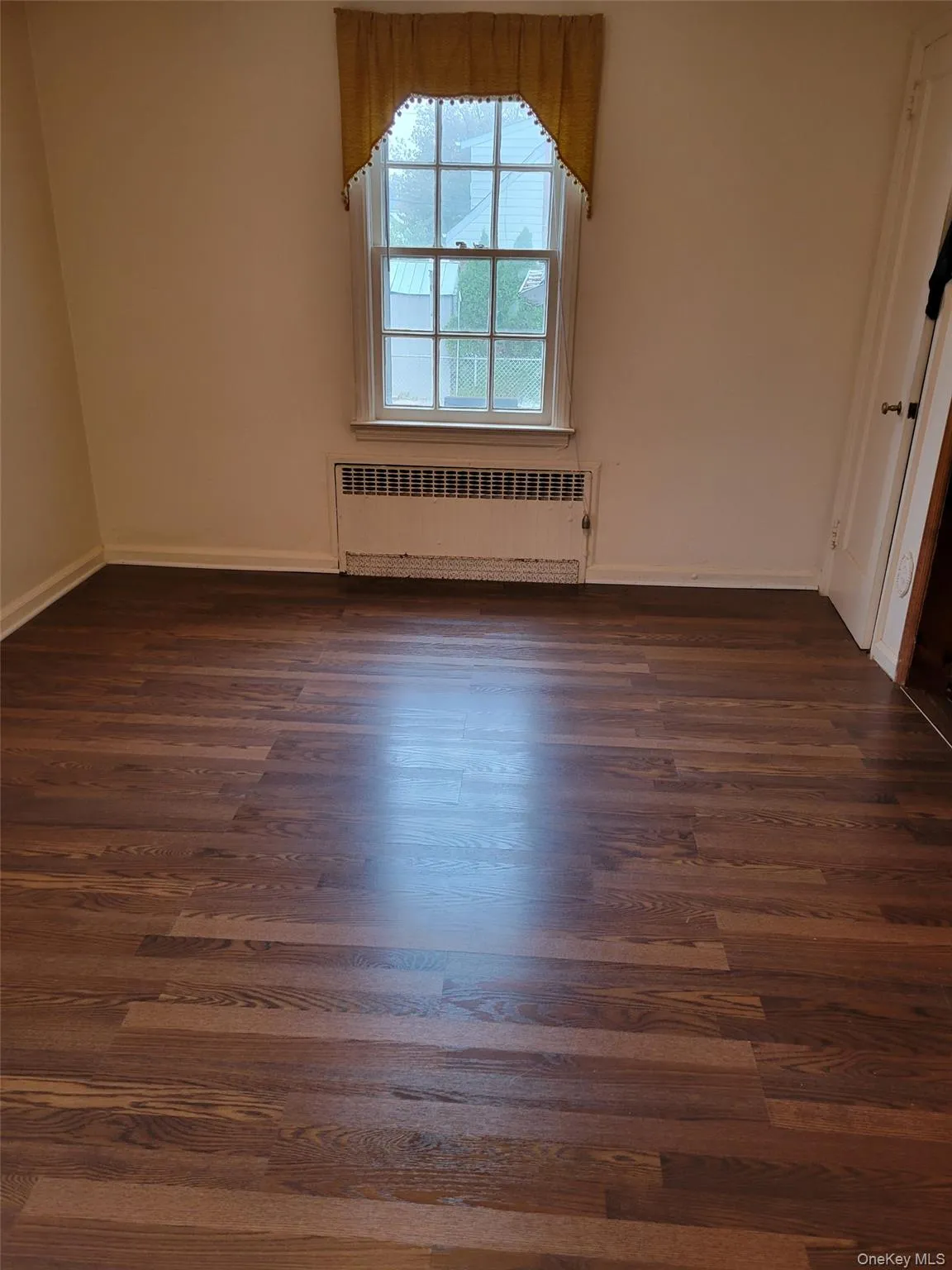 Spare room featuring dark wood finished floors and radiator Spare room featuring dark wood finished floors and radiator