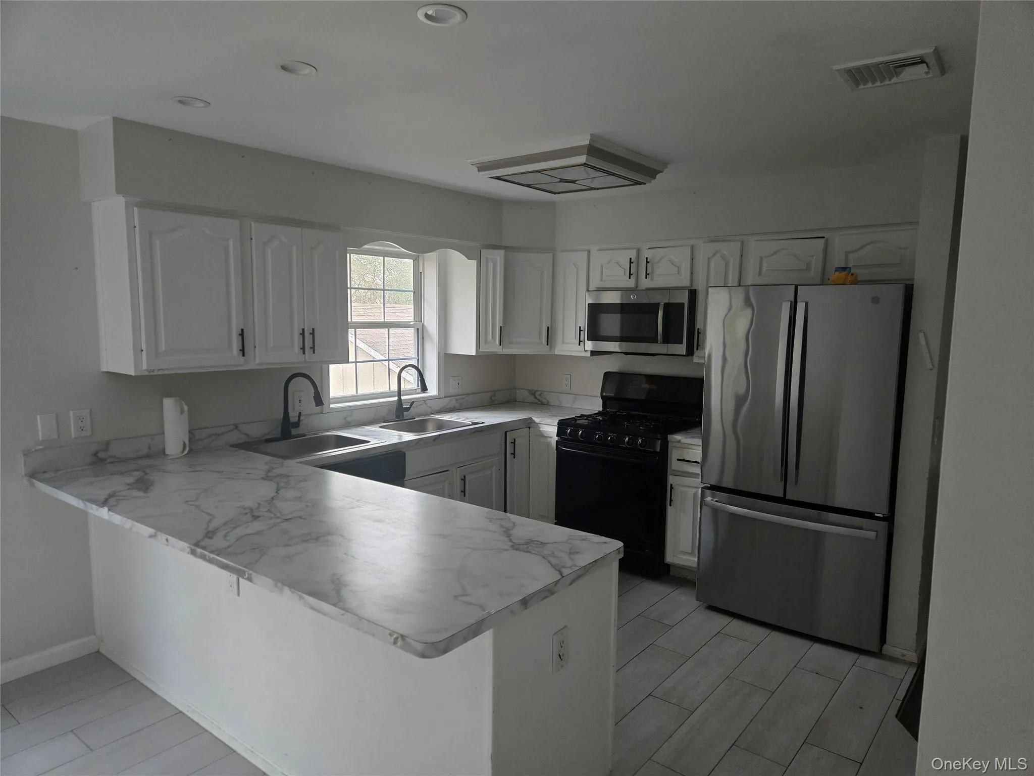 Kitchen featuring appliances with stainless steel finishes, a peninsula, white cabinets, light countertops, and recessed lighting Kitchen featuring appliances with stainless steel finishes, a peninsula, white cabinets, light countertops, and recessed lighting