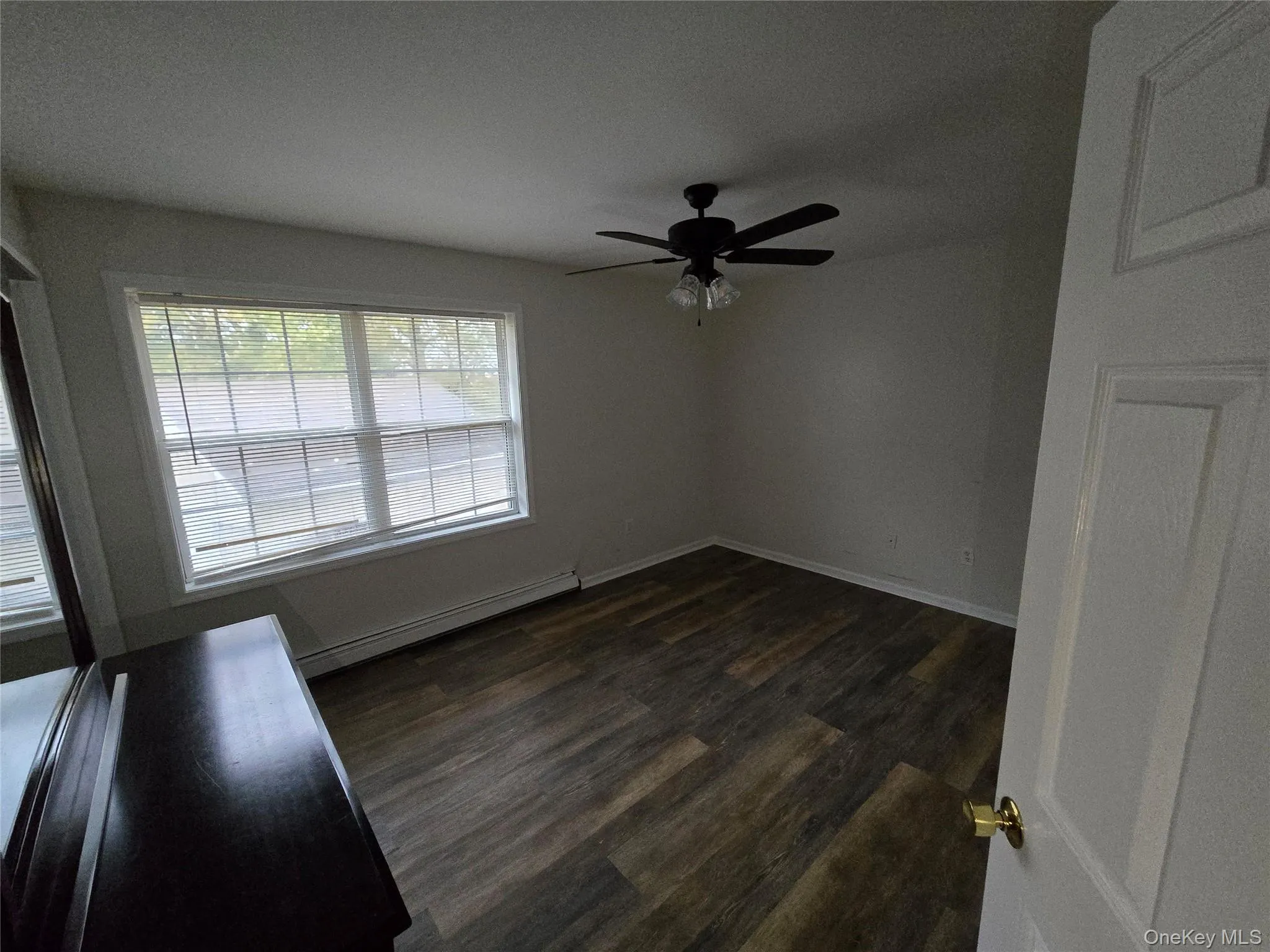 Spare room with a baseboard radiator, dark wood finished floors, and a ceiling fan Spare room with a baseboard radiator, dark wood finished floors, and a ceiling fan
