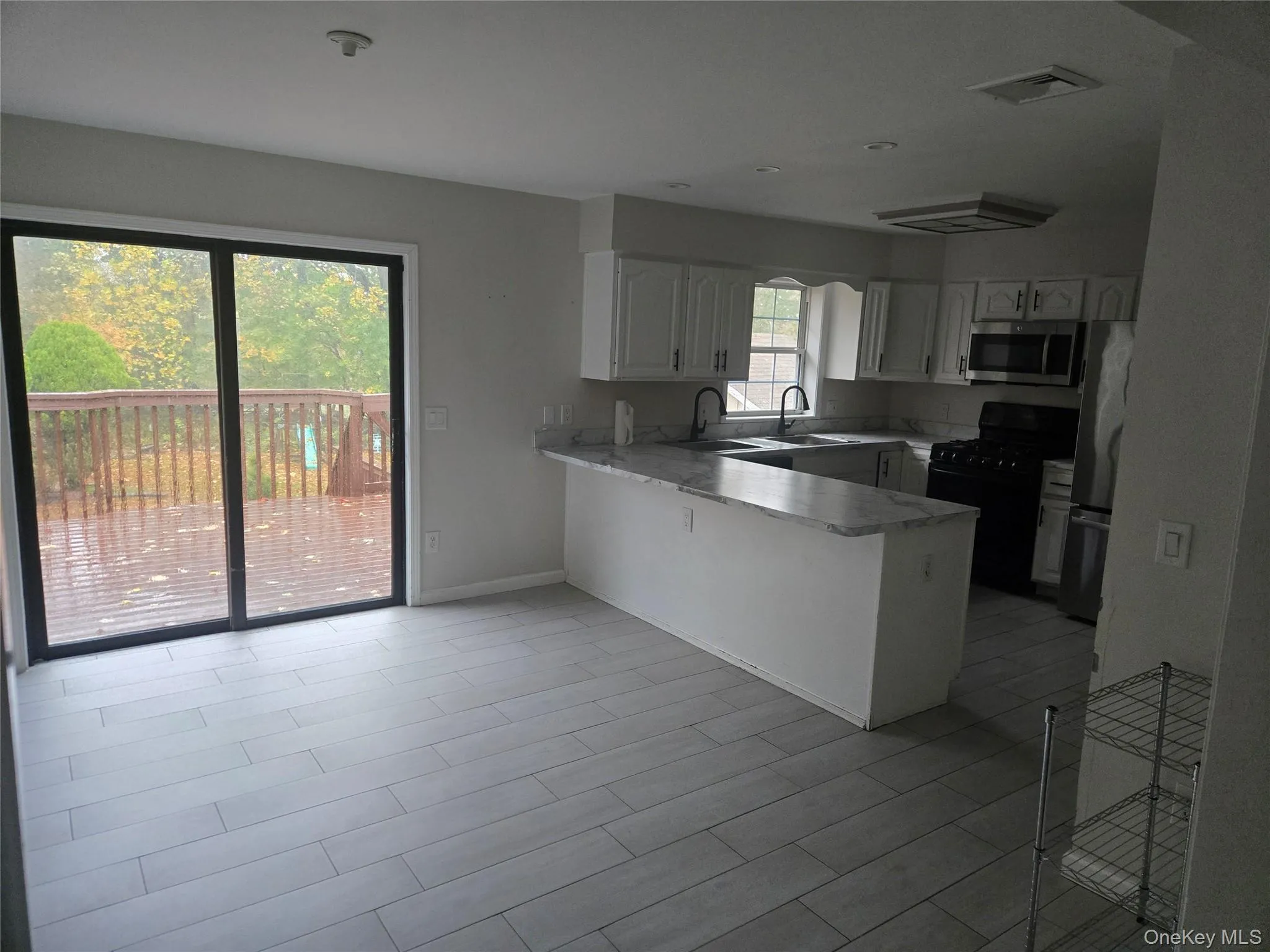 Kitchen with a peninsula, stainless steel appliances, light countertops, and white cabinets Kitchen with a peninsula, stainless steel appliances, light countertops, and white cabinets
