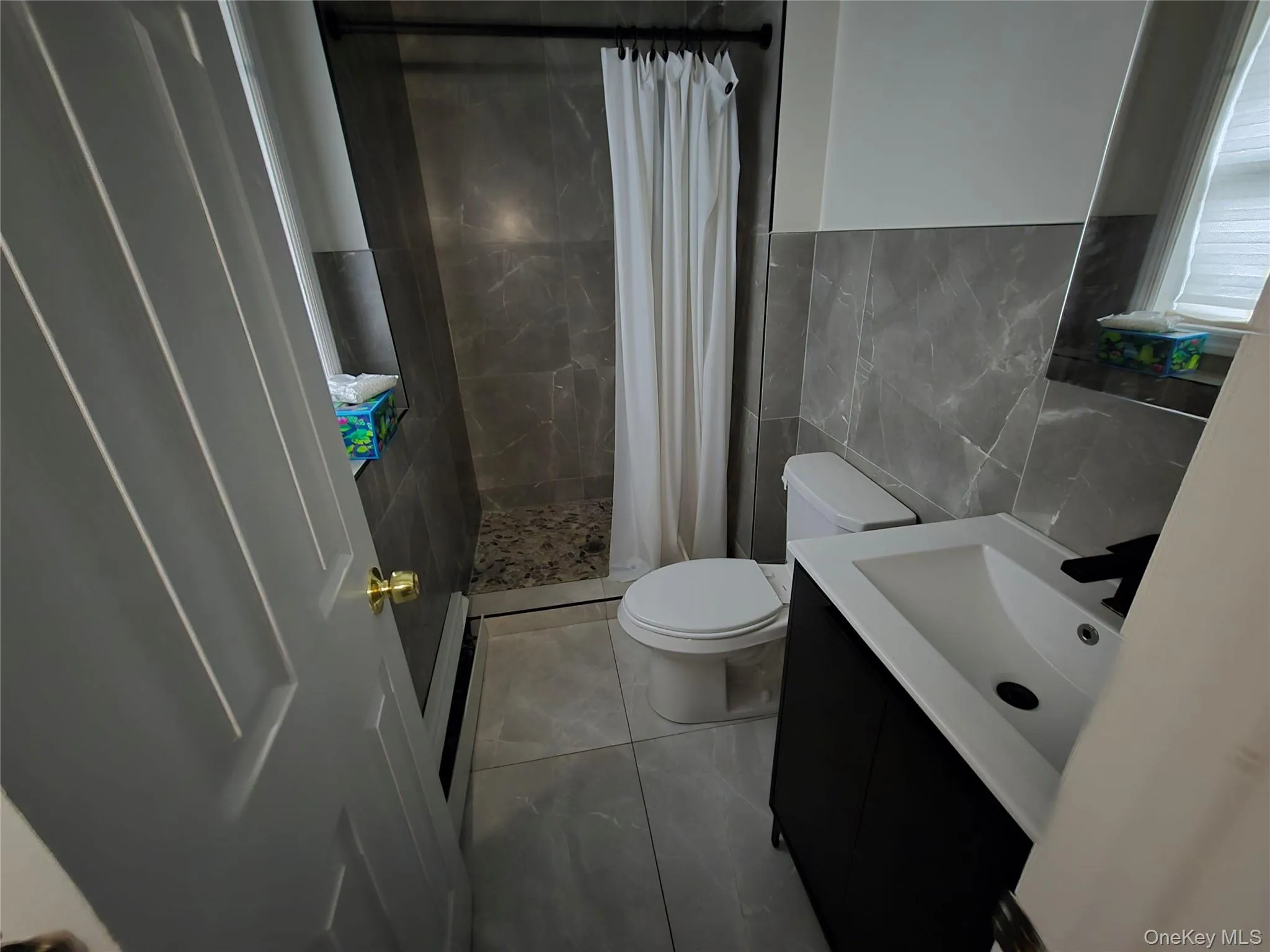 Bathroom featuring vanity, a stall shower, and tile walls Bathroom featuring vanity, a stall shower, and tile walls