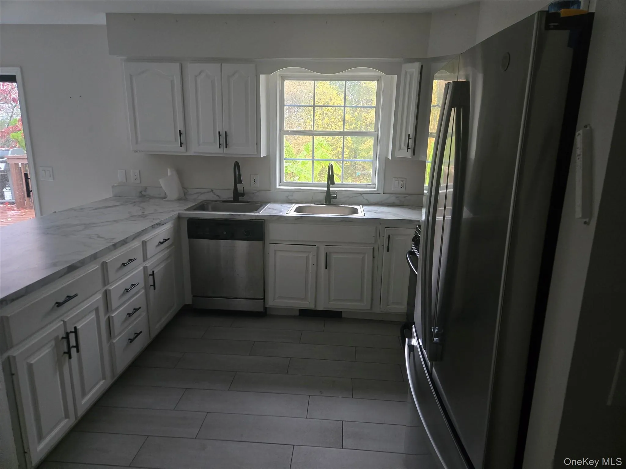 Kitchen featuring white cabinetry, stainless steel appliances, light countertops, and a peninsula Kitchen featuring white cabinetry, stainless steel appliances, light countertops, and a peninsula