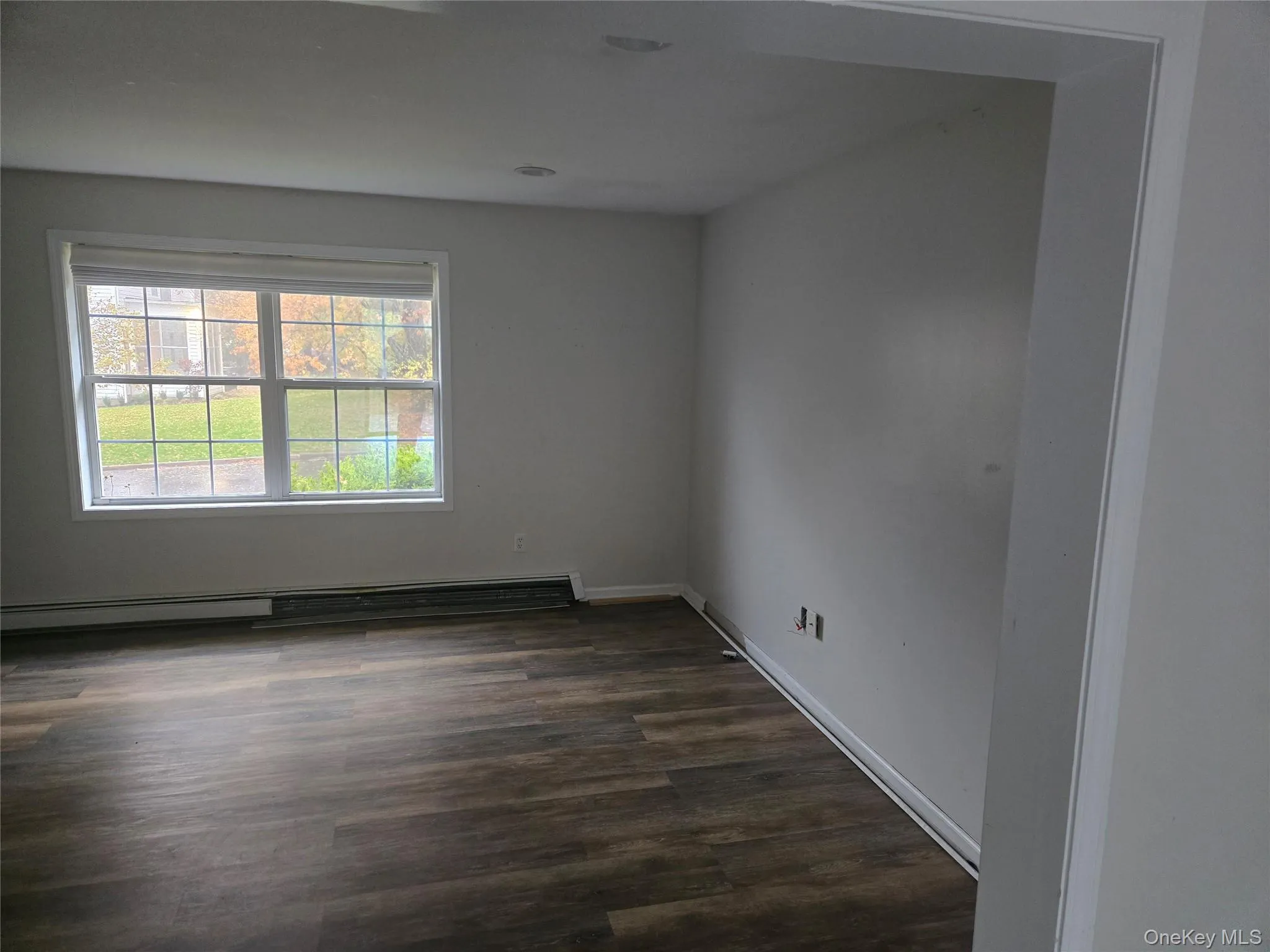 Unfurnished room featuring dark wood-style floors and a baseboard radiator Unfurnished room featuring dark wood-style floors and a baseboard radiator