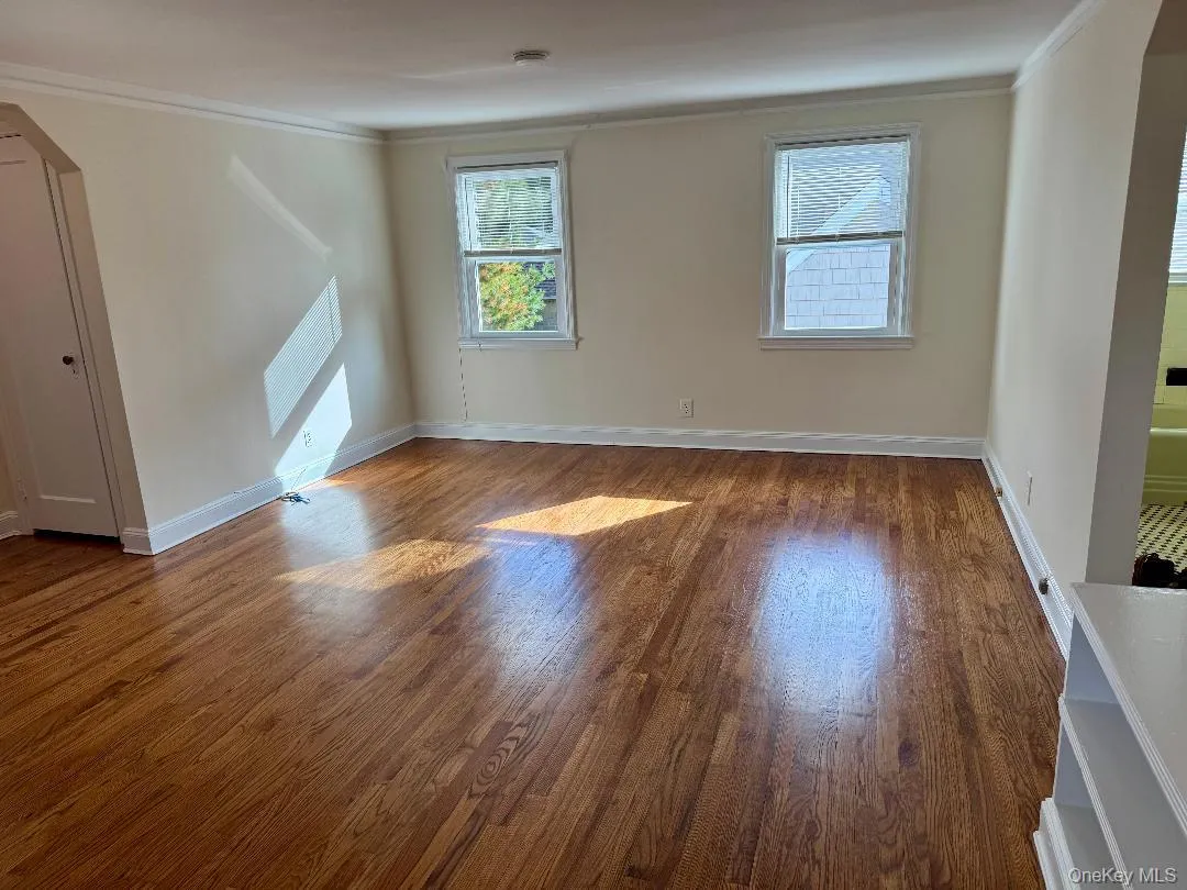 Unfurnished room with arched walkways, crown molding, and wood finished floors Unfurnished room with arched walkways, crown molding, and wood finished floors