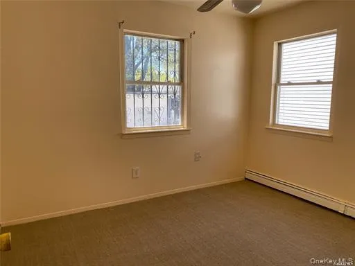 Carpeted empty room with ceiling fan and a baseboard heating unit Carpeted empty room with ceiling fan and a baseboard heating unit