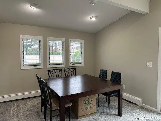 Dining area with light carpet, healthy amount of natural light, a baseboard radiator, and beam ceiling Dining area with light carpet, healthy amount of natural light, a baseboard radiator, and beam ceiling