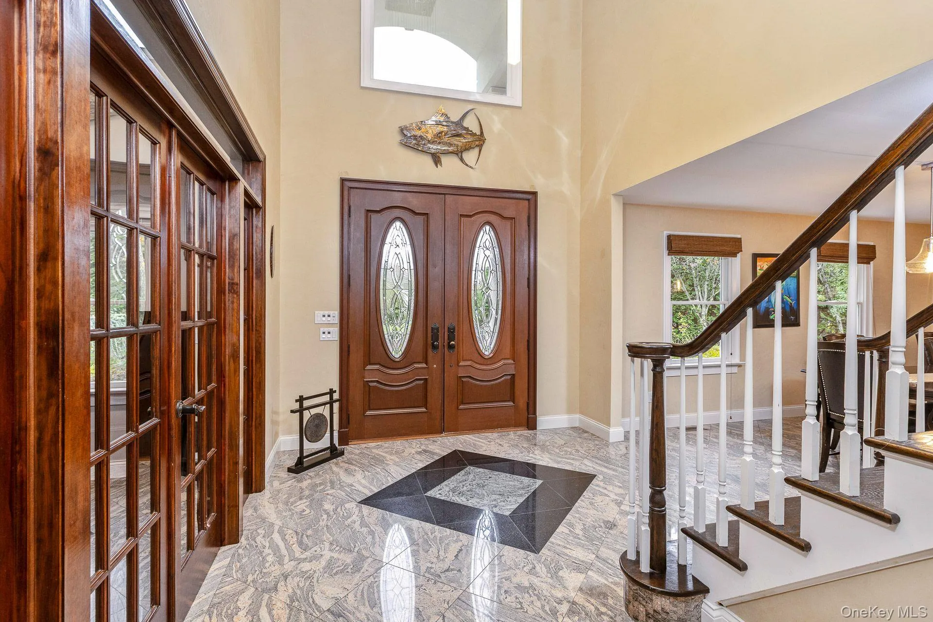 Entryway featuring french doors, a towering ceiling, light marble finish floors, and stairway Entryway featuring french doors, a towering ceiling, light marble finish floors, and stairway