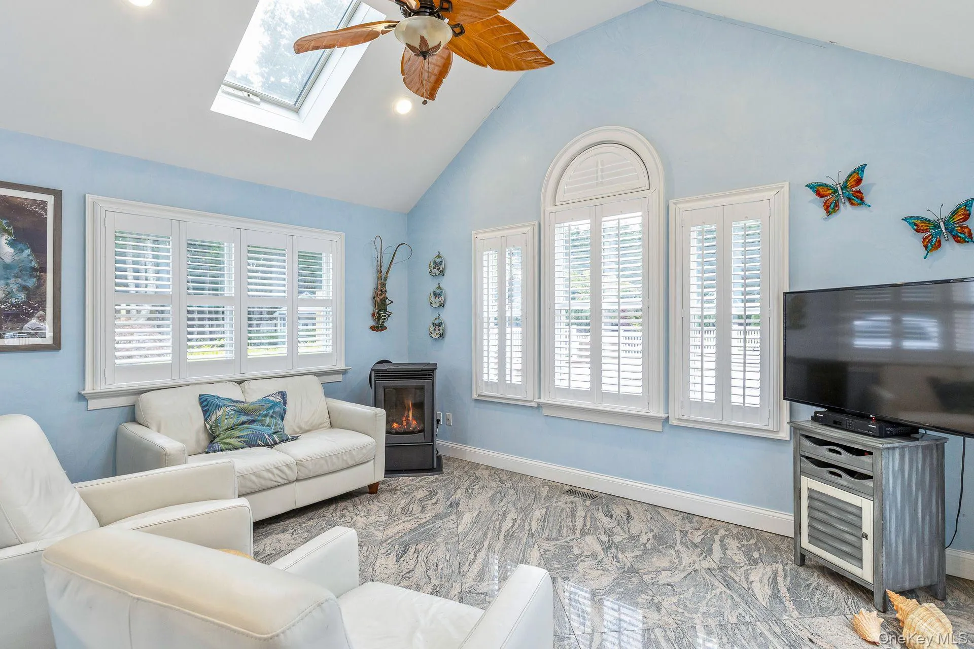 Living area featuring a ceiling fan, high vaulted ceiling, a wood stove, a skylight, and recessed lighting Living area featuring a ceiling fan, high vaulted ceiling, a wood stove, a skylight, and recessed lighting
