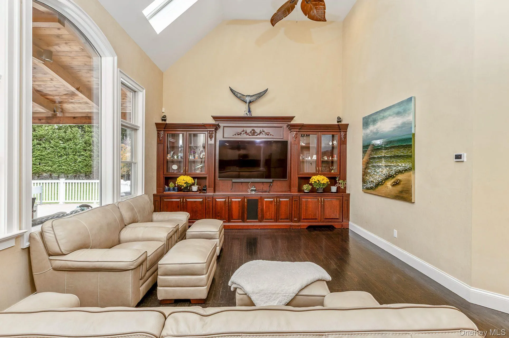 Living room with high vaulted ceiling, dark wood-style flooring, a skylight, and a ceiling fan Living room with high vaulted ceiling, dark wood-style flooring, a skylight, and a ceiling fan