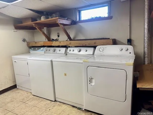 Washroom featuring washer and clothes dryer and a drop ceiling Washroom featuring washer and clothes dryer and a drop ceiling