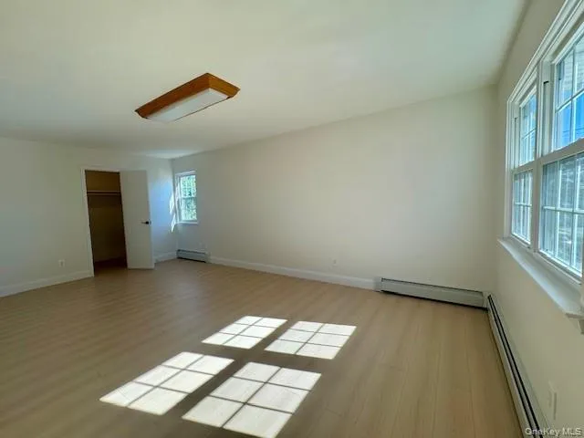 Unfurnished bedroom with a baseboard radiator and light wood finished floors Unfurnished bedroom with a baseboard radiator and light wood finished floors