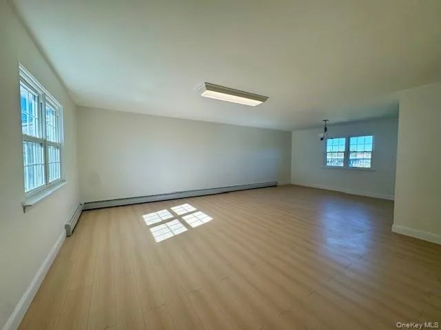 Spare room with light wood finished floors and baseboard heating Spare room with light wood finished floors and baseboard heating