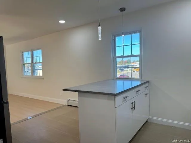 Kitchen featuring white cabinetry, a peninsula, hanging light fixtures, healthy amount of natural light, and recessed lighting Kitchen featuring white cabinetry, a peninsula, hanging light fixtures, healthy amount of natural light, and recessed lighting