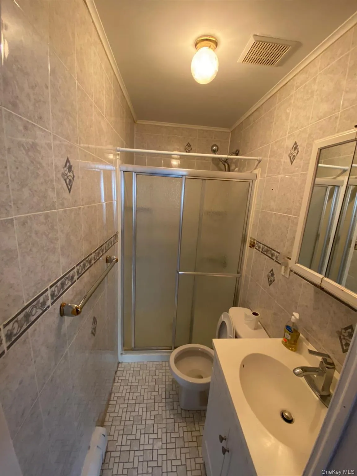 Bathroom with tile walls, a shower stall, vanity, crown molding, and light tile patterned floors Bathroom with tile walls, a shower stall, vanity, crown molding, and light tile patterned floors