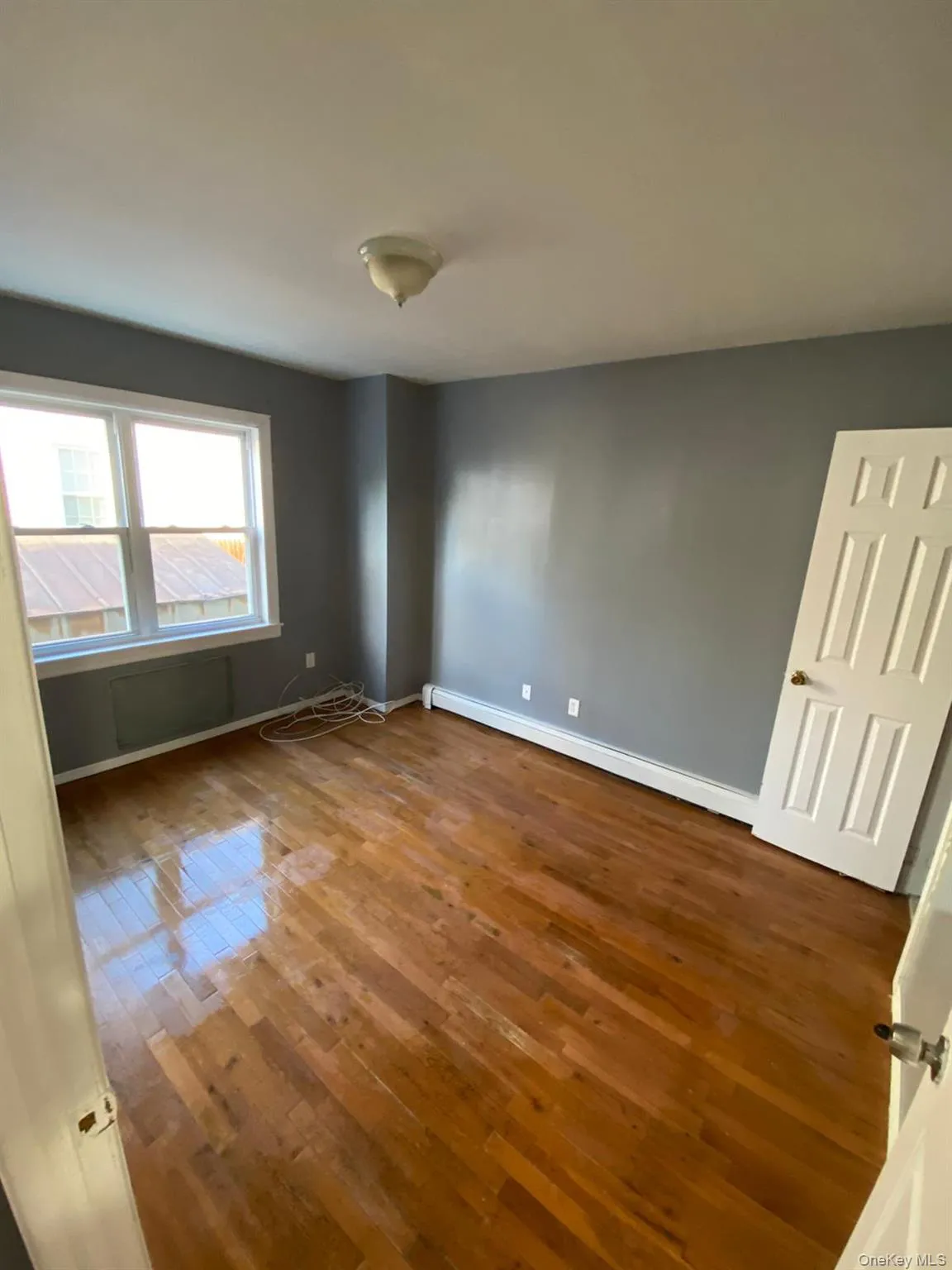 Empty room featuring dark wood-style flooring and baseboard heating Empty room featuring dark wood-style flooring and baseboard heating