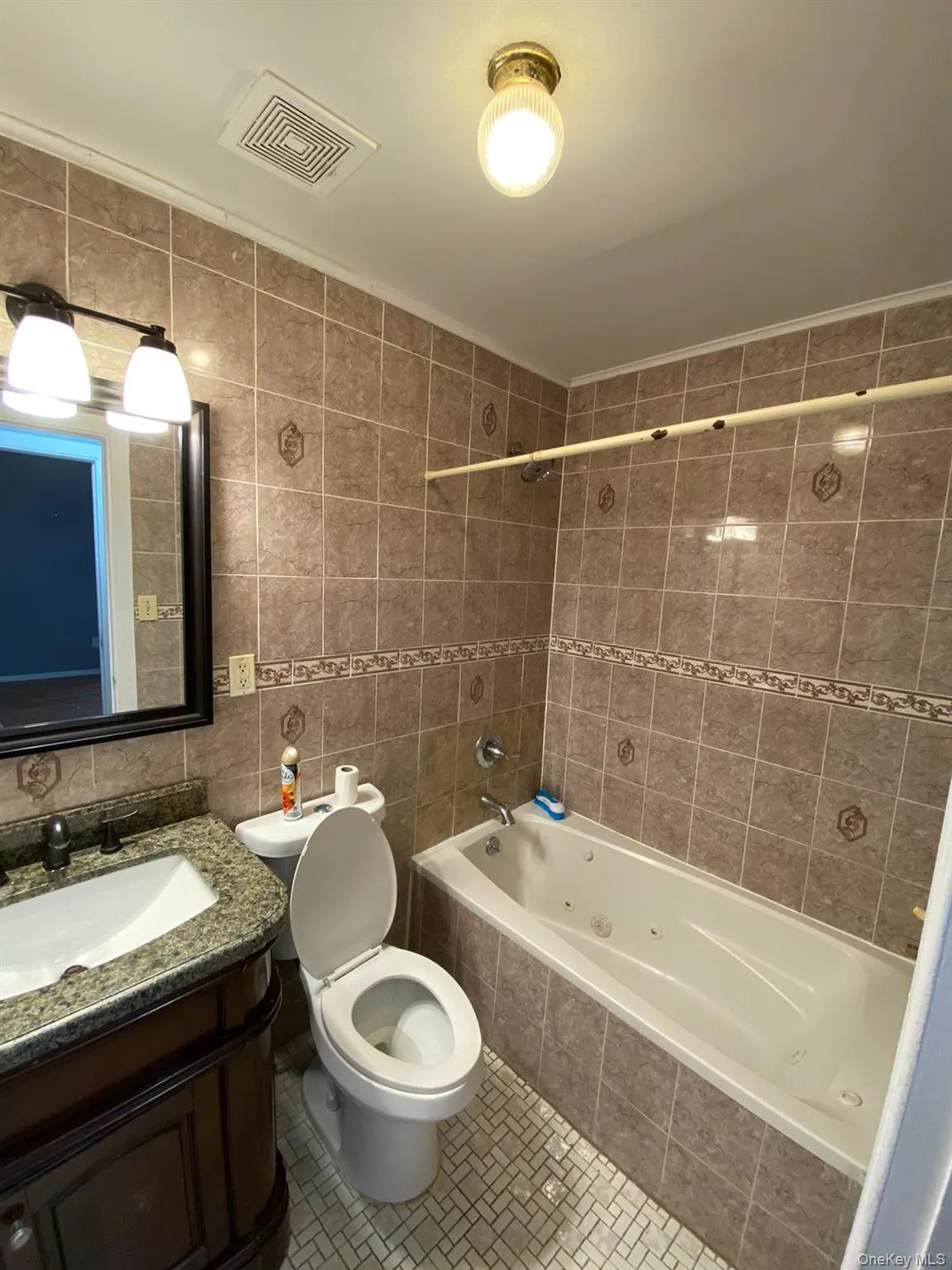 Full bath with tile walls, vanity, a combined bath / shower with jetted tub, tile patterned flooring, and backsplash Full bath with tile walls, vanity, a combined bath / shower with jetted tub, tile patterned flooring, and backsplash