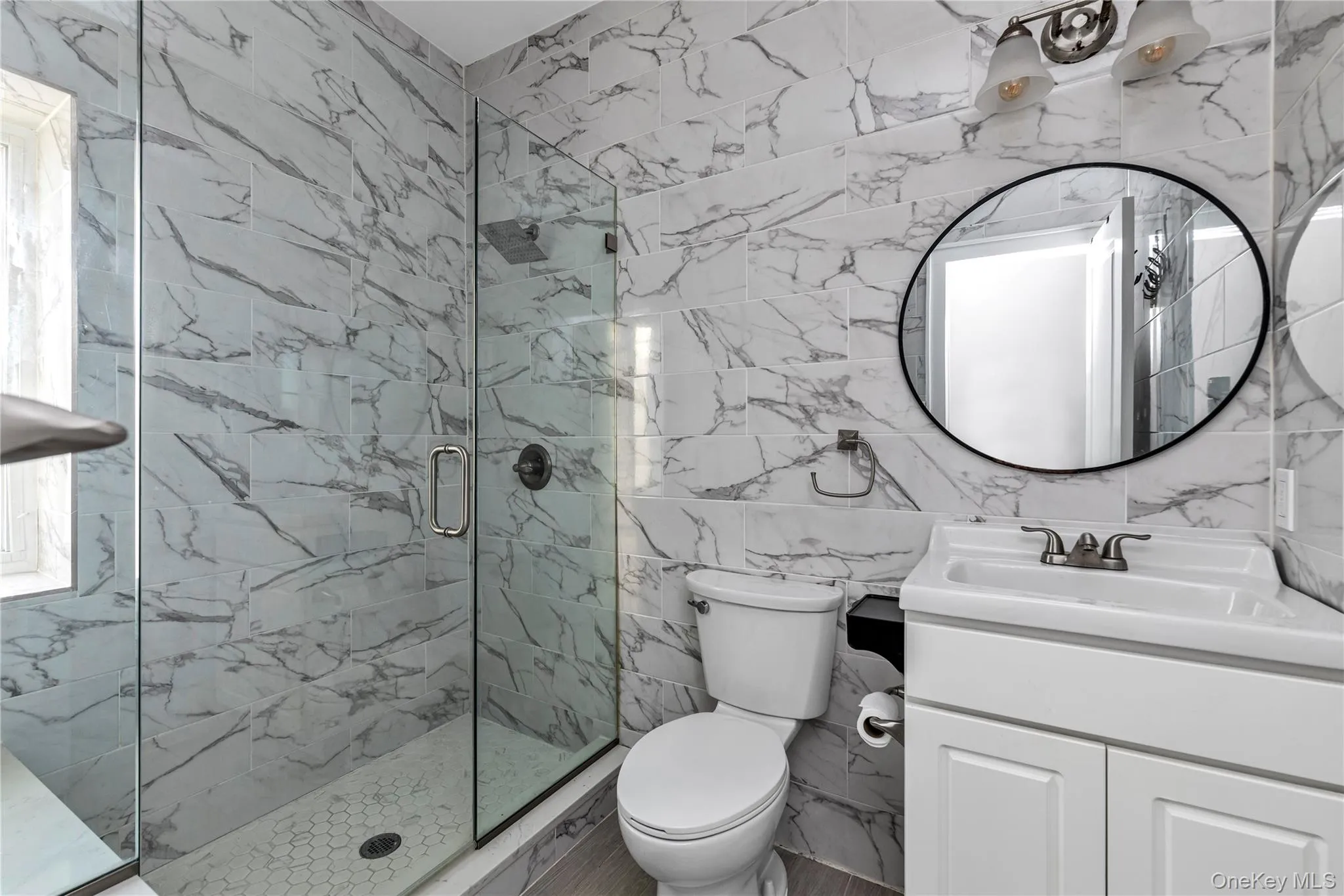Full bathroom with tile walls, vanity, and a marble finish shower Full bathroom with tile walls, vanity, and a marble finish shower
