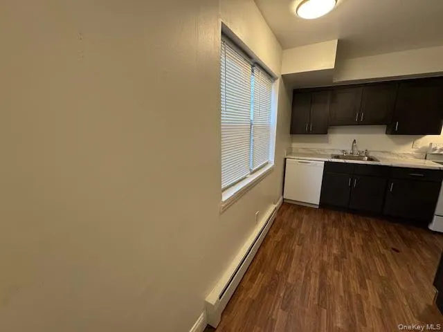 Kitchen featuring a baseboard radiator, light countertops, dishwasher, dark wood-style floors, and range Kitchen featuring a baseboard radiator, light countertops, dishwasher, dark wood-style floors, and range