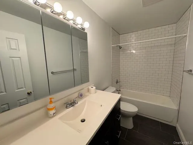 Bathroom with vanity, bathtub / shower combination, and dark tile patterned flooring Bathroom with vanity, bathtub / shower combination, and dark tile patterned flooring
