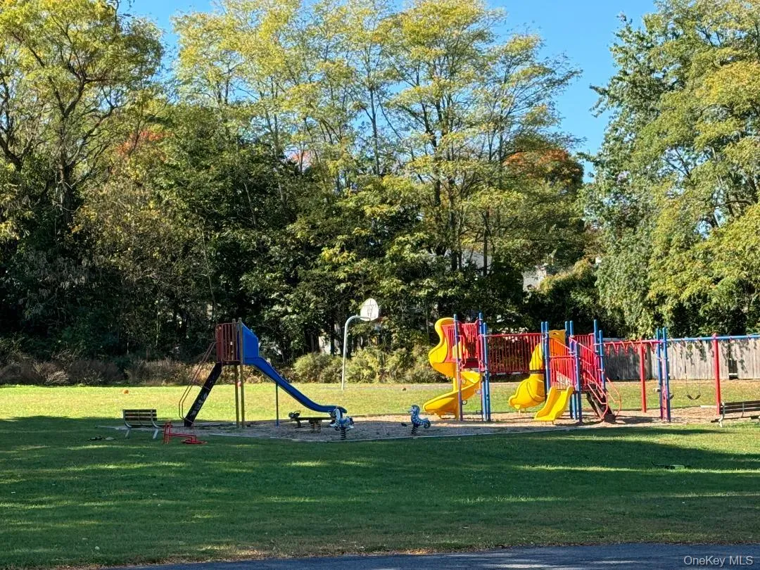Community playground with a yard and view of wooded area Community playground with a yard and view of wooded area