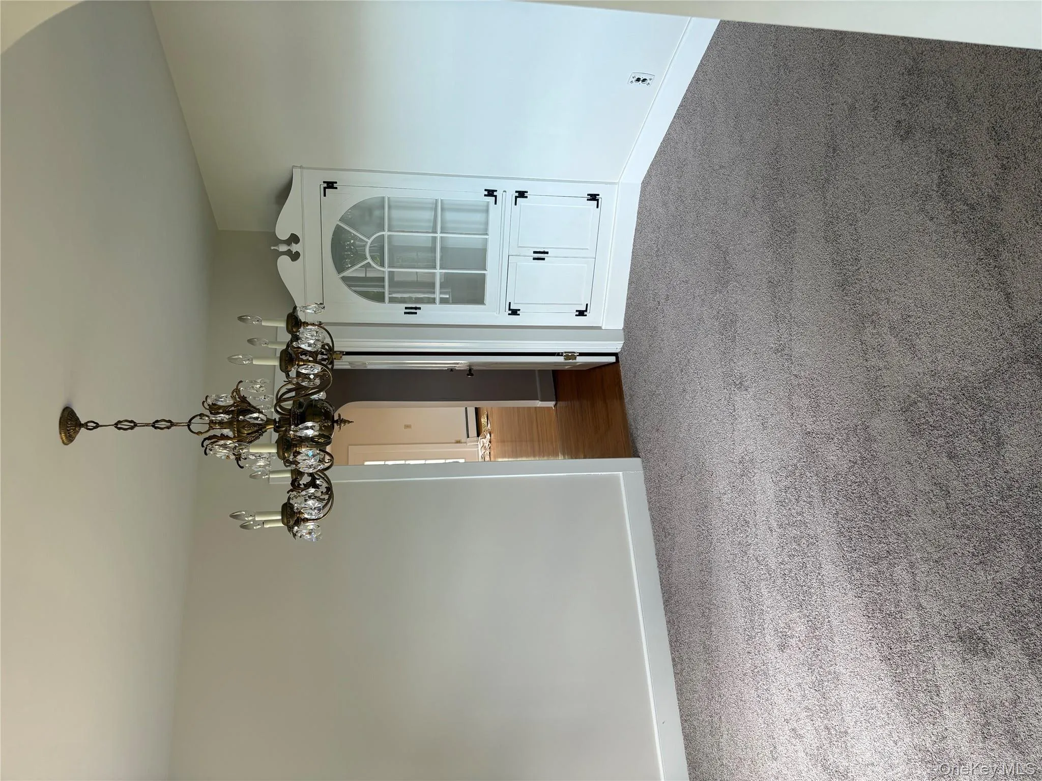 Unfurnished dining area with arched walkways, carpet floors, and a chandelier Unfurnished dining area with arched walkways, carpet floors, and a chandelier