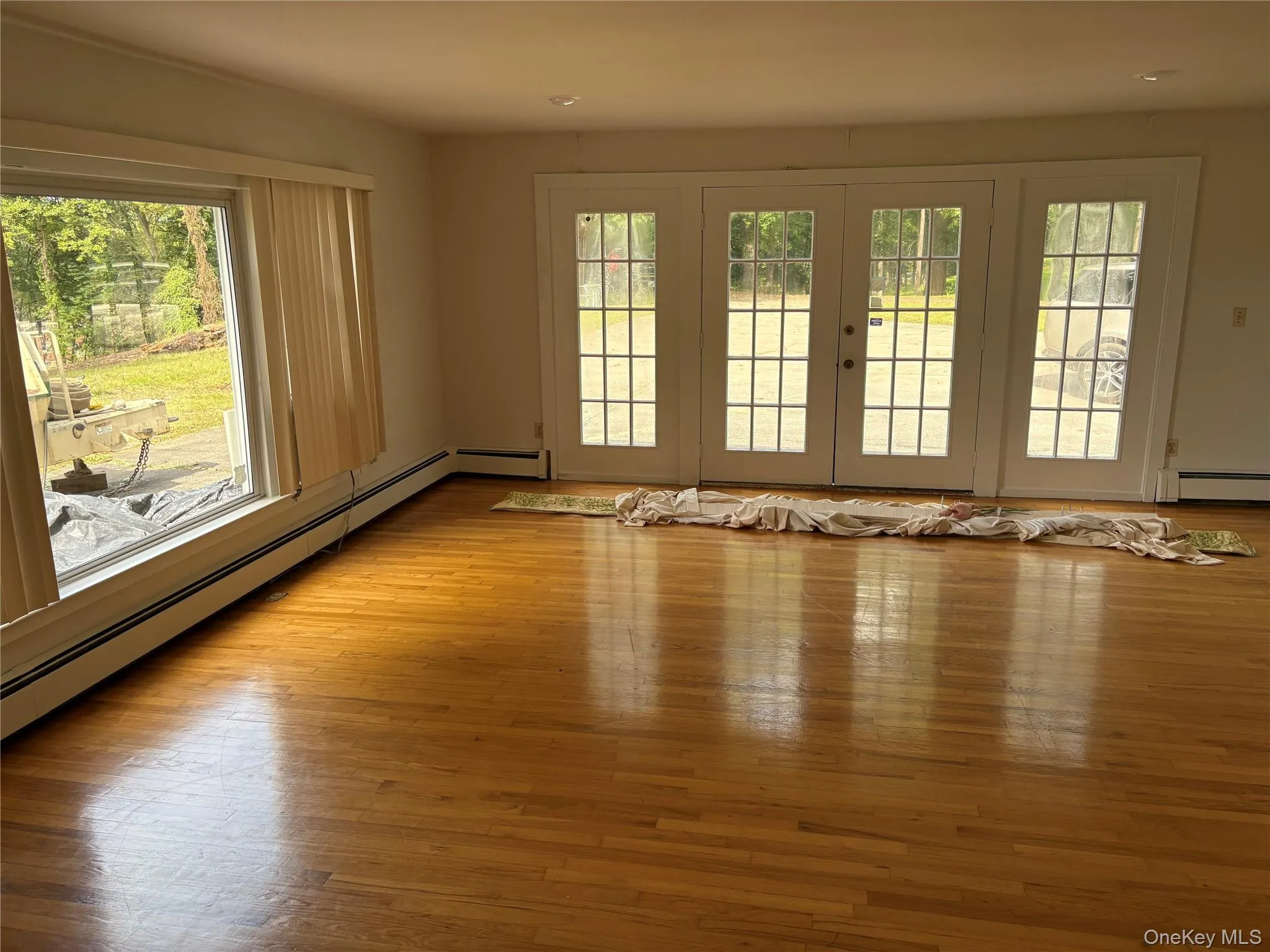 Unfurnished room featuring baseboard heating, healthy amount of natural light, and light wood-type flooring Unfurnished room featuring baseboard heating, healthy amount of natural light, and light wood-type flooring