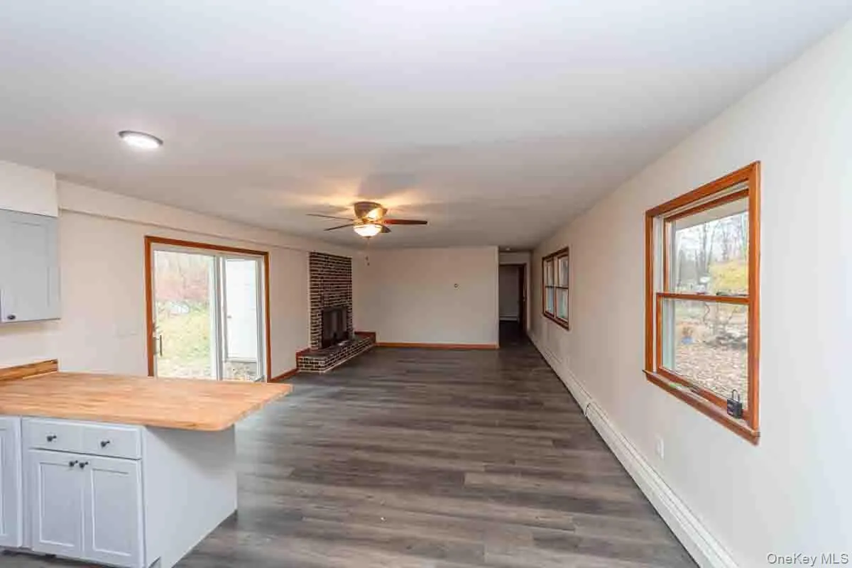 Unfurnished living room featuring dark wood-style flooring, ceiling fan, baseboard heating, a fireplace, and recessed lighting Unfurnished living room featuring dark wood-style flooring, ceiling fan, baseboard heating, a fireplace, and recessed lighting