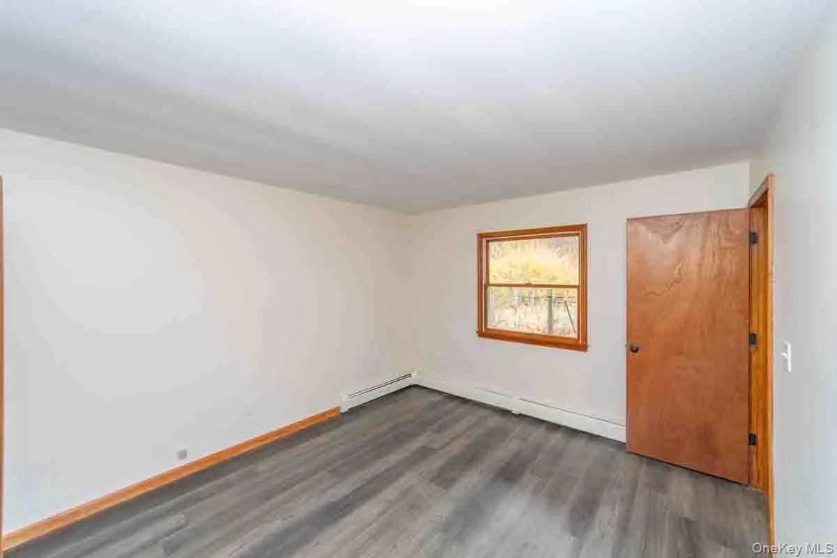 Spare room featuring dark wood finished floors and baseboard heating Spare room featuring dark wood finished floors and baseboard heating