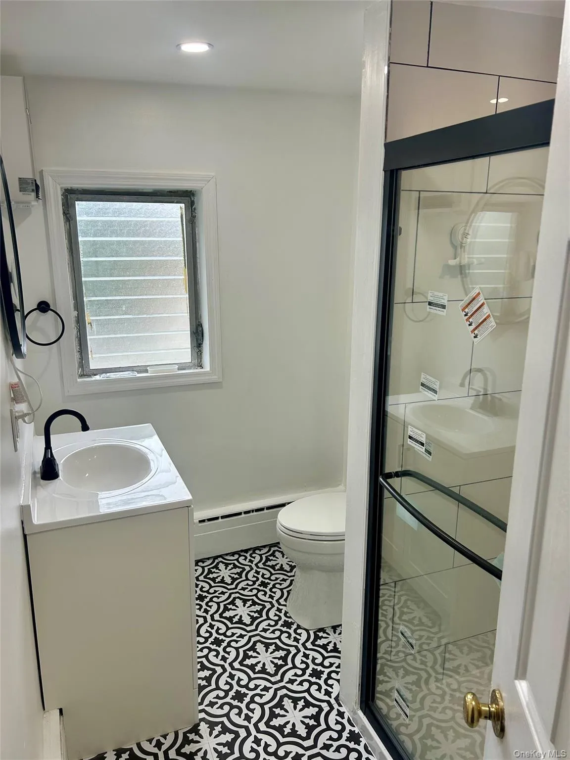 Bathroom featuring vanity, a stall shower, a baseboard heating unit, and tile patterned floors Bathroom featuring vanity, a stall shower, a baseboard heating unit, and tile patterned floors