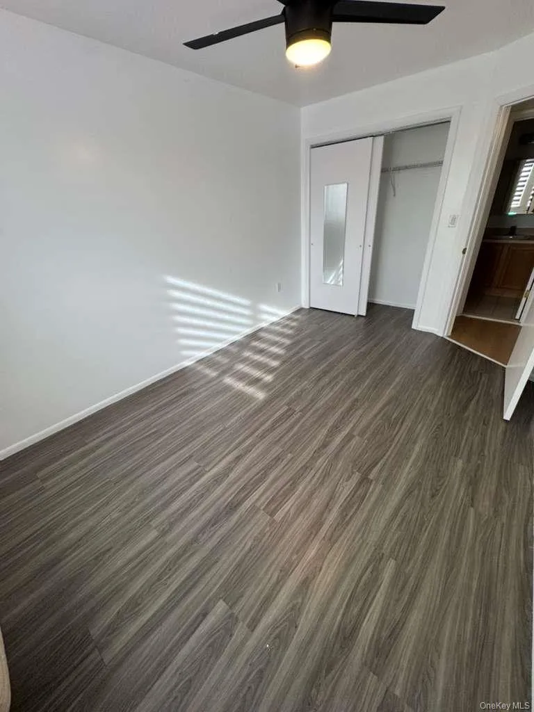 Unfurnished bedroom featuring dark wood-style flooring, a closet, and a ceiling fan Unfurnished bedroom featuring dark wood-style flooring, a closet, and a ceiling fan