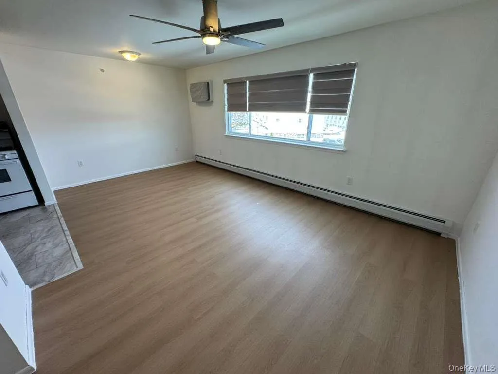 Unfurnished room with a baseboard heating unit, light wood-type flooring, and a ceiling fan Unfurnished room with a baseboard heating unit, light wood-type flooring, and a ceiling fan