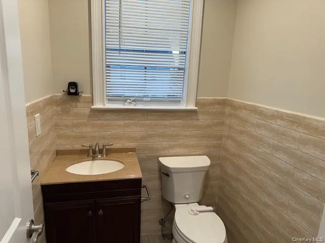 Half bath with vanity, a wainscoted wall, and tile walls Half bath with vanity, a wainscoted wall, and tile walls