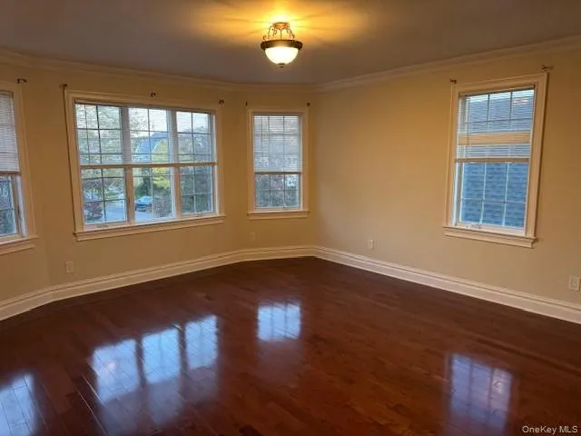 Empty room featuring crown molding and dark wood-type flooring Empty room featuring crown molding and dark wood-type flooring