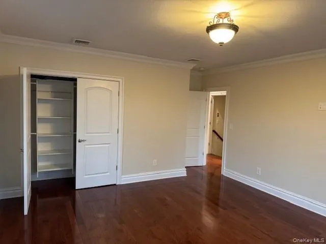 Unfurnished bedroom featuring crown molding, dark wood-style flooring, a closet, and a textured ceiling Unfurnished bedroom featuring crown molding, dark wood-style flooring, a closet, and a textured ceiling