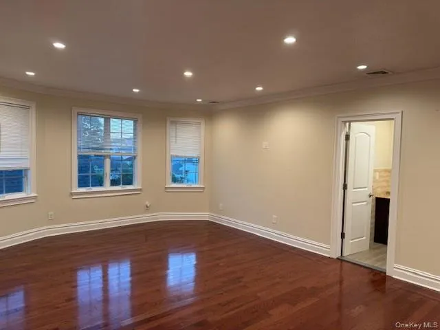 Empty room featuring crown molding, recessed lighting, and dark wood-style floors Empty room featuring crown molding, recessed lighting, and dark wood-style floors