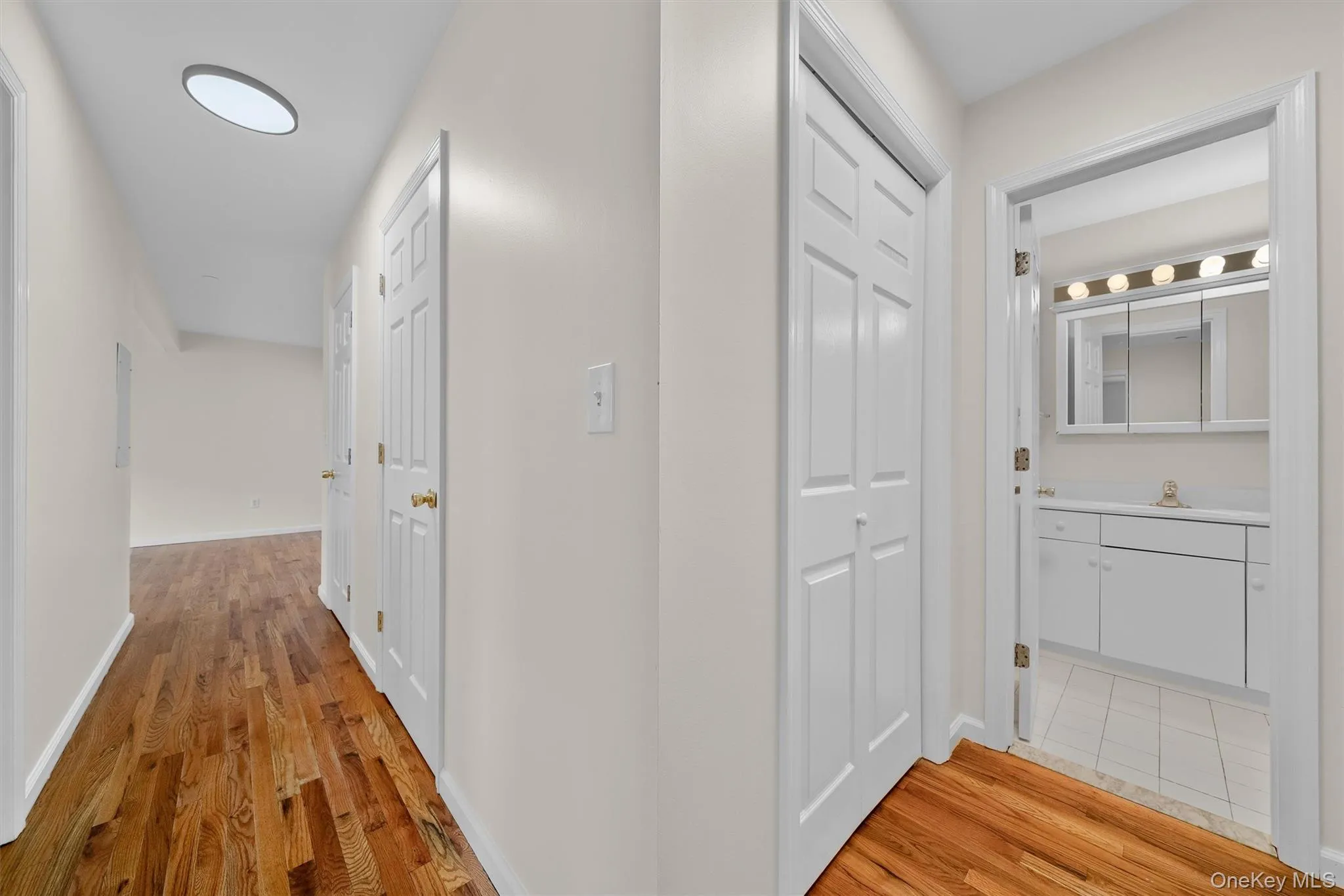 Hall featuring a sink, light wood-style floors, and baseboards Hall featuring a sink, light wood-style floors, and baseboards