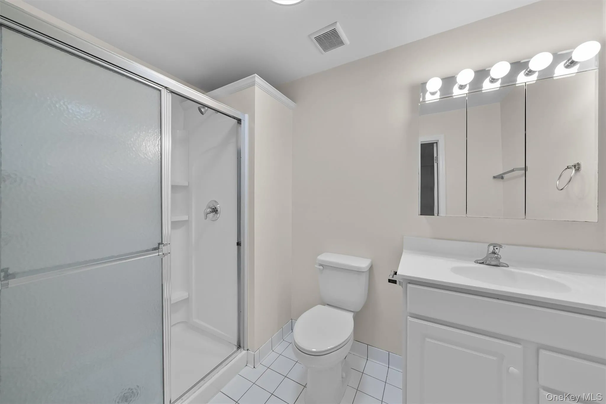 Full bath featuring tile patterned flooring, toilet, vanity, visible vents, and a stall shower Full bath featuring tile patterned flooring, toilet, vanity, visible vents, and a stall shower