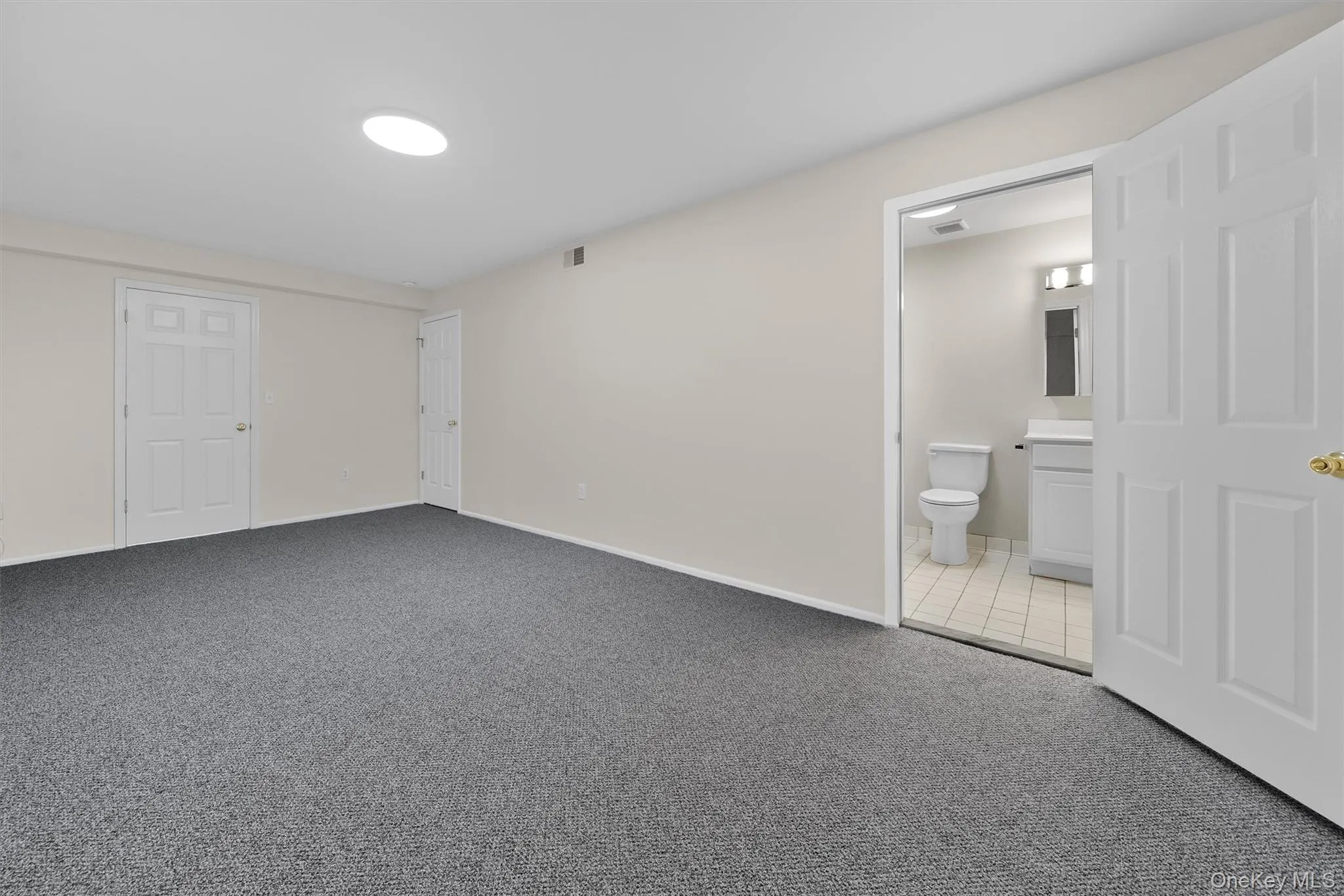 Unfurnished bedroom with baseboards, visible vents, ensuite bath, and carpet floors Unfurnished bedroom with baseboards, visible vents, ensuite bath, and carpet floors