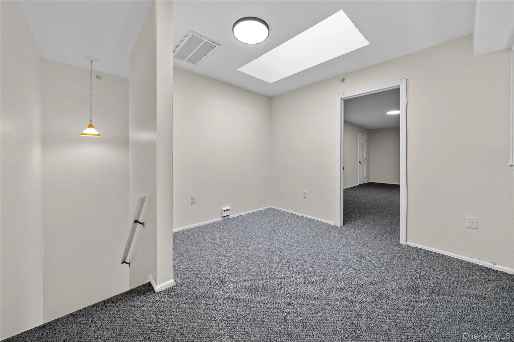 Spare room featuring dark carpet, visible vents, baseboards, and a skylight Spare room featuring dark carpet, visible vents, baseboards, and a skylight
