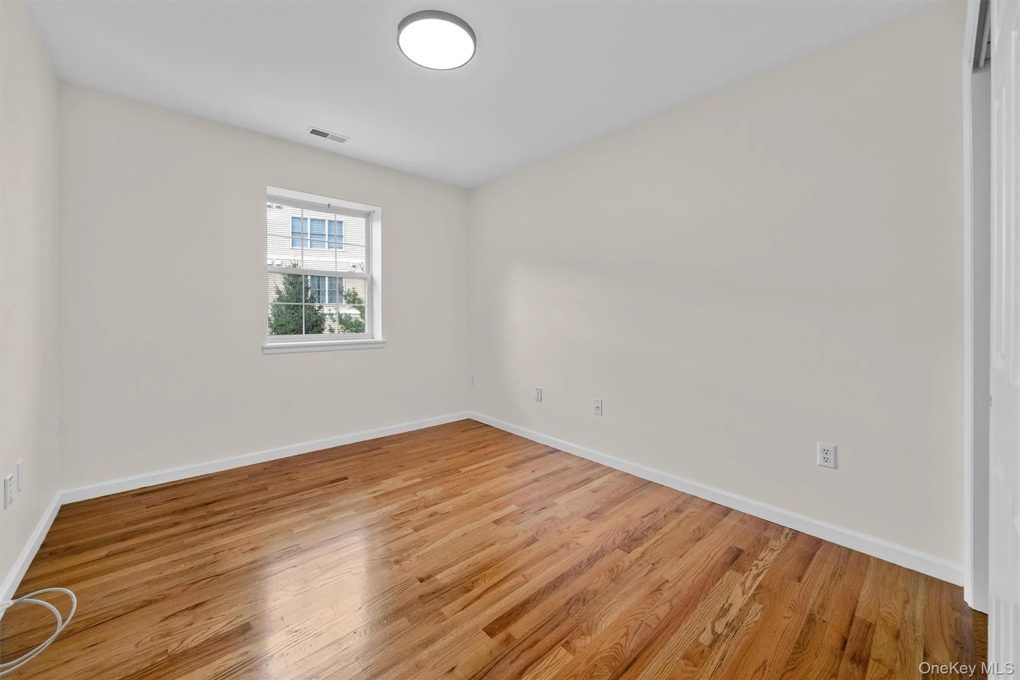 Empty room with baseboards, visible vents, and light wood-style flooring Empty room with baseboards, visible vents, and light wood-style flooring