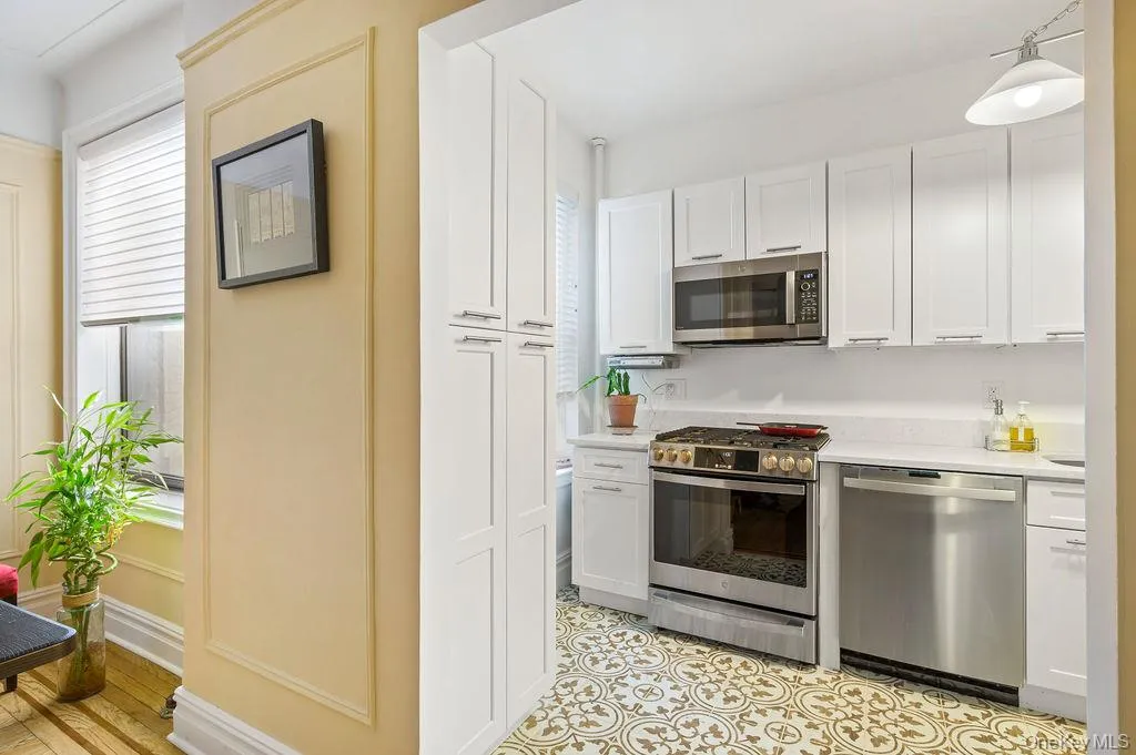 Kitchen featuring stainless steel appliances, white cabinetry, and hanging light fixtures Kitchen featuring stainless steel appliances, white cabinetry, and hanging light fixtures