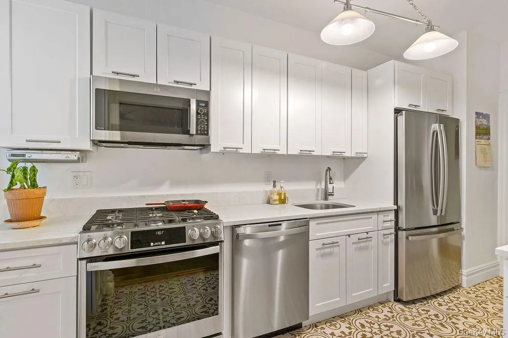 Kitchen with appliances with stainless steel appliances, white cabinets, light stone counters. Kitchen with appliances with stainless steel appliances, white cabinets, light stone counters.