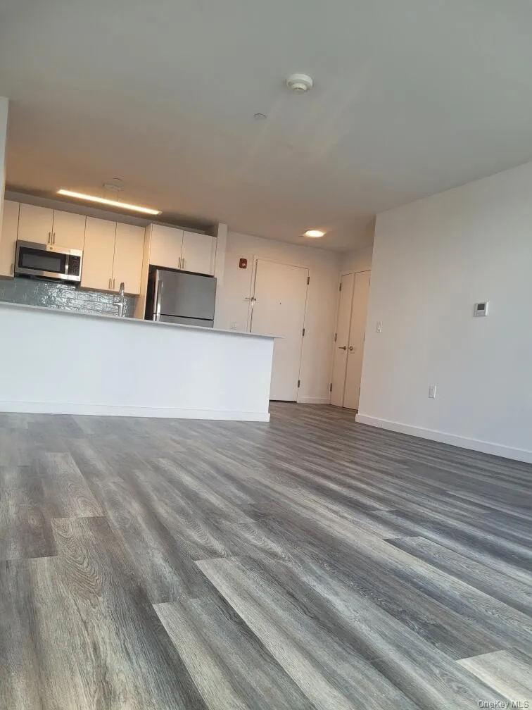 Unfurnished living room featuring dark wood finished floors and baseboards Unfurnished living room featuring dark wood finished floors and baseboards