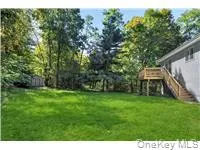 View of grassy yard featuring stairs and a deck View of grassy yard featuring stairs and a deck
