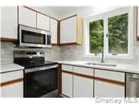 Kitchen with appliances with stainless steel finishes, brown cabinetry, light countertops, tasteful backsplash, and white cabinetry Kitchen with appliances with stainless steel finishes, brown cabinetry, light countertops, tasteful backsplash, and white cabinetry