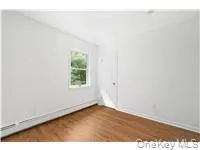 Unfurnished room featuring dark wood-type flooring and a baseboard heating unit Unfurnished room featuring dark wood-type flooring and a baseboard heating unit